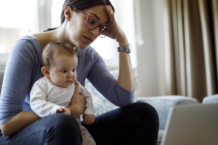 Worried woman with baby looking at computer