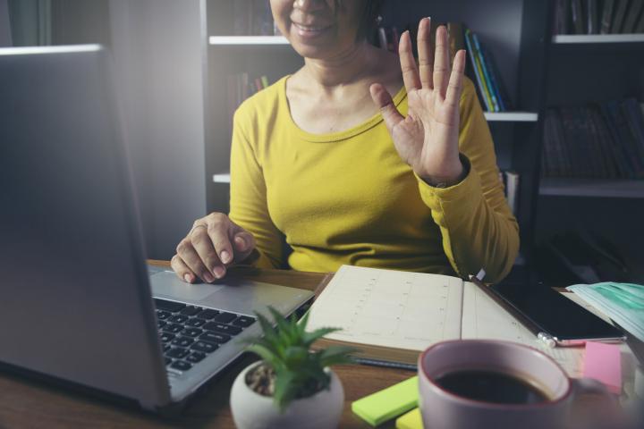 Woman waving hi to people in zoom meeting