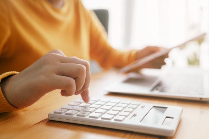 Person using calculator and laptop computer