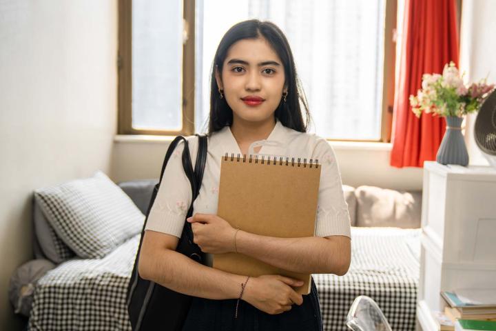 young woman holding school notebook in living room