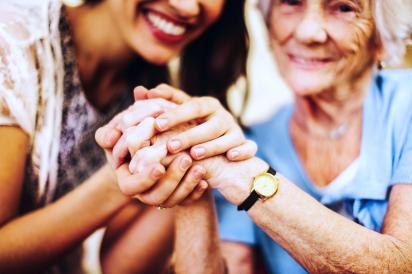 Care aide holding hands of elderly resident