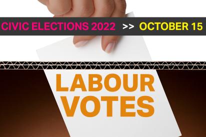 Hand putting ballot into a ballot box. Labour votes is written on the ballot box.