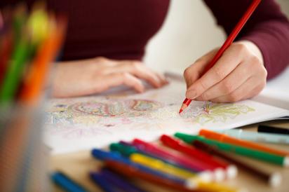 Image of hands colouring on a page with pencil crayons in the foreground