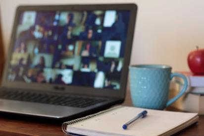 Open laptop on a desk with coffee cup, notebook and pen