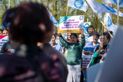 HEU members at a PNP rally. Members holds up sign that says: Keep experienced health care workers in B.C.