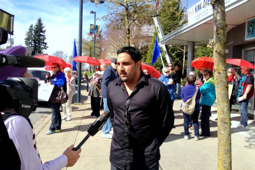 Rally organizer Kelly Aujla speaks to media in front of Surrey MP Nina Grewal's office